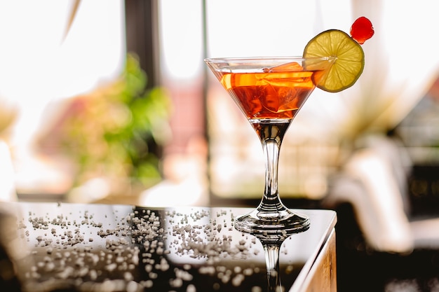 Side view of alcoholic cocktail manhattan with bourbon red vemuth bitter ice and cocktail cherry in glass