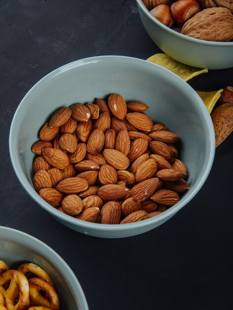 Side view of almond in a bowl on black