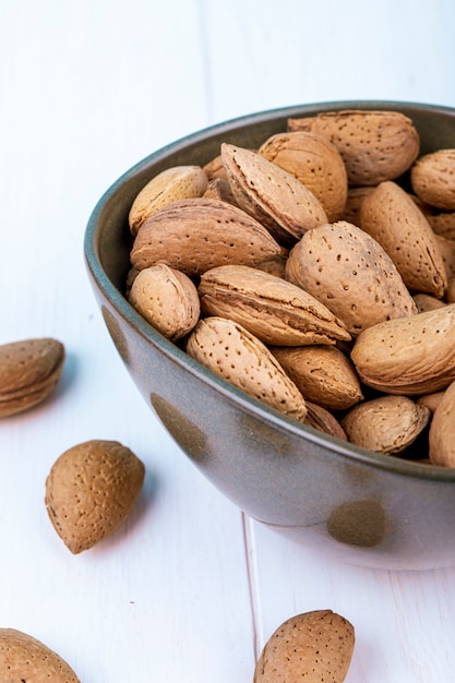 Side view of almonds in shell in a bowl on white background