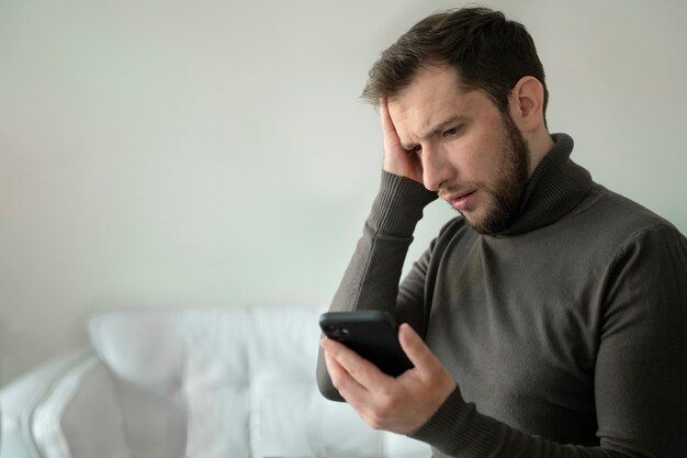 Side view anxious man holding smartphone