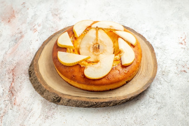 Free photo side view appetizing cake appetizing pear cake on the wooden board on the white surface