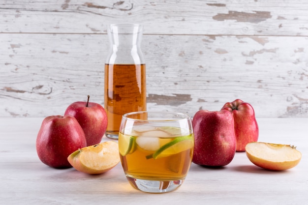 Вид сбоку яблочный сок на белом деревянном столе