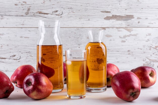 흰색 나무 테이블에 빨간 사과와 측면보기 사과 주스