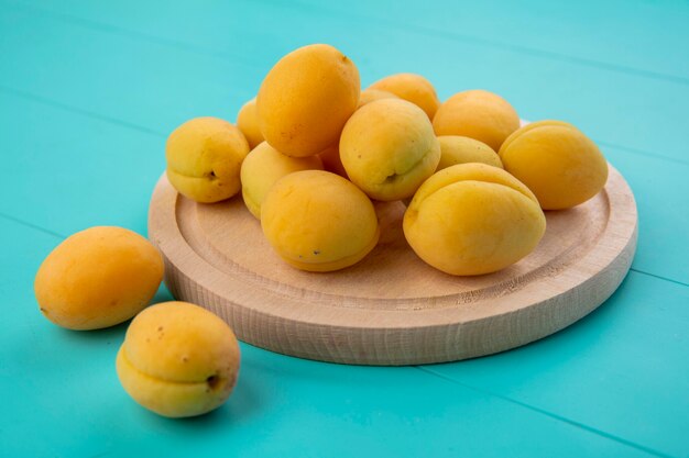 Side view of apricots on a stand on a blue surface