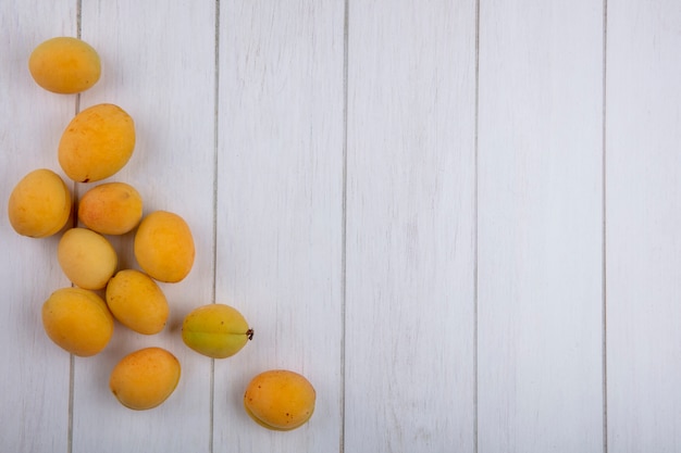 Side view of apricots on a white surface