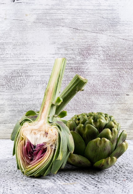 Side view artichoke and slice on light gray background. vertical space for text