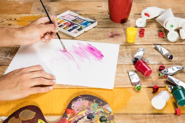 Side view of artist using paint brush on paper