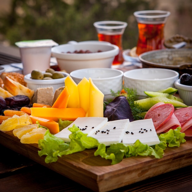 Colazione assortita vista laterale con vassoio di formaggio e salsicce di vetro del tè in vassoio di legno sul ristorante