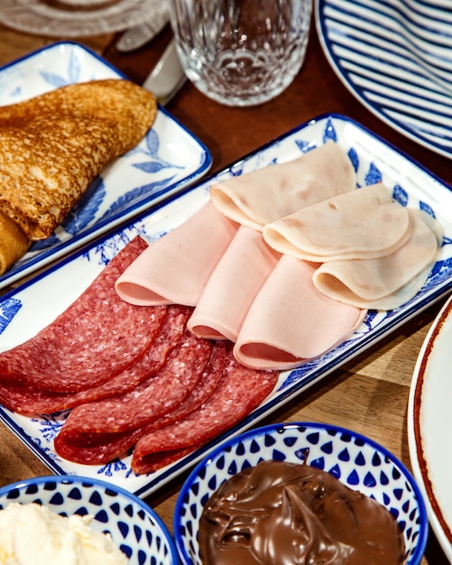 Free photo side view of assortment of delicious deli meats on platter