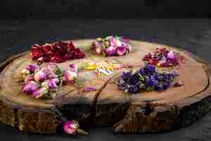 Free photo side view of assortment of dry flower and rose tea on wooden board on black