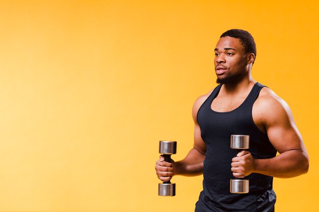 Side view of athlete holding weights with copy space