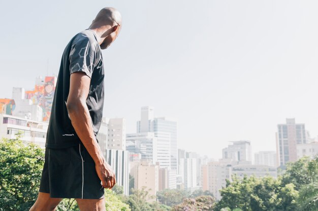 Free photo side view of a athlete young man looking at city skyline