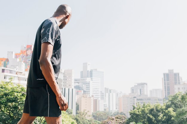 Foto gratuita vista laterale di un giovane atleta guardando skyline della città