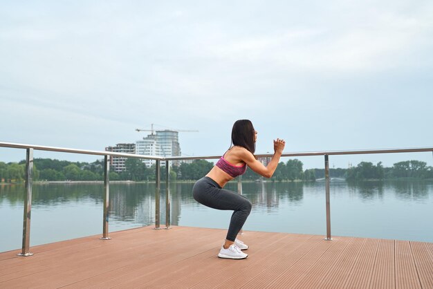 Side view of athletic girl doing squat exercises outdoor