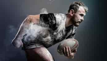 Free photo side view of athletic male rugby player holding ball with dust