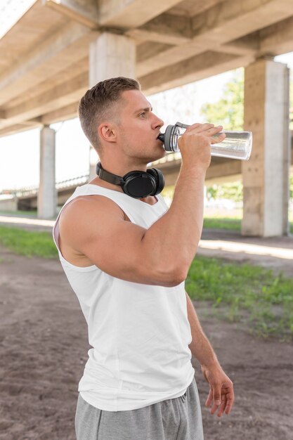 Side view athletic man drinking water