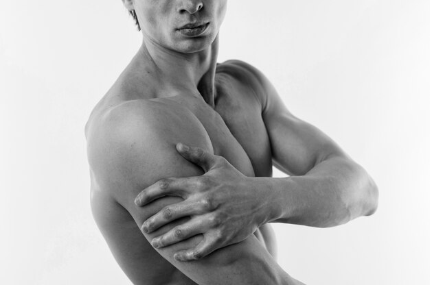 Side view of athletic man posing shirtless in black and white