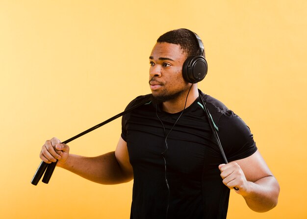 Side view of athletic man with headphones and jumping rope