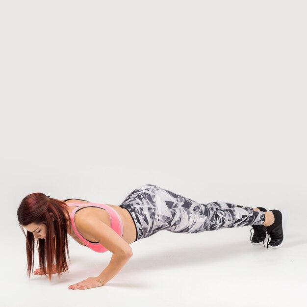 Side view of athletic woman doing push-ups