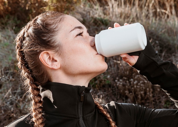 Free photo side view of athletic woman drinking soda