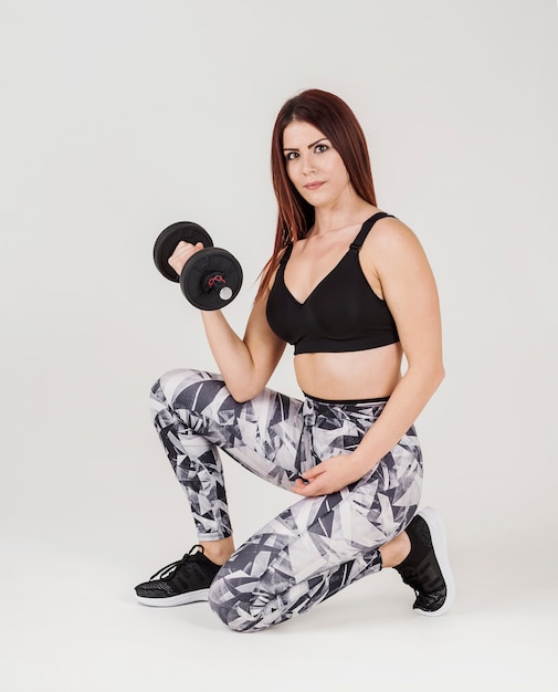 Side view of athletic woman lifting weight