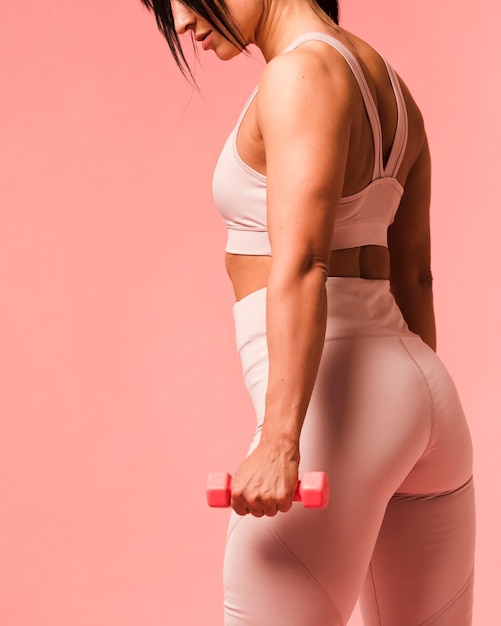 Side view of athletic woman posing with weights