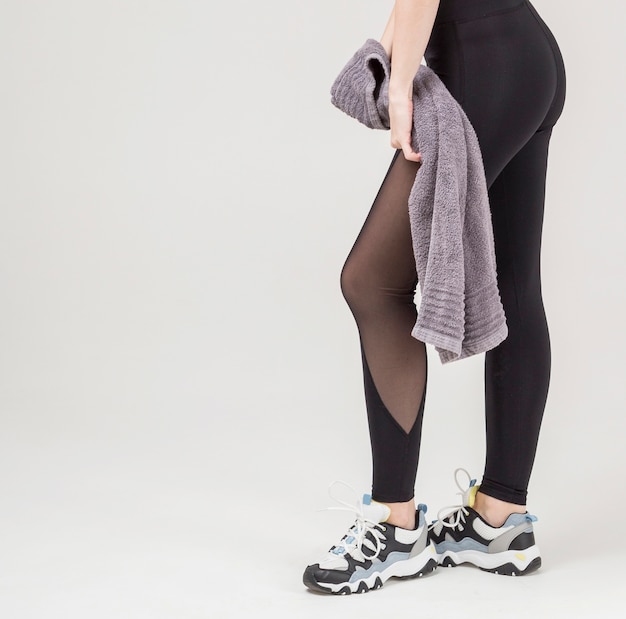 Side view of athletic woman's legs posing while holding a towel