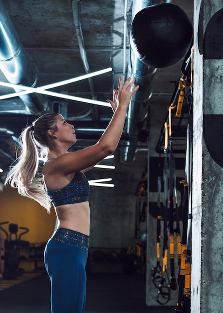 Side view of an athletic woman throwing medicine ball in gym