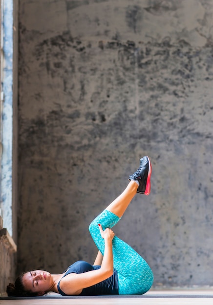 Free photo side view of an athletic young woman doing yoga on exercise mat