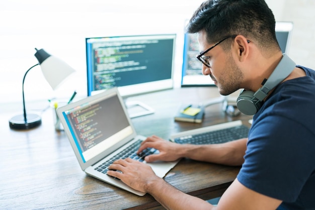 Free photo side view of attractive hispanic developer programming software using computer while working from home