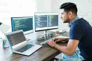 Free photo side view of attractive hispanic software developer programming using computer while working from home