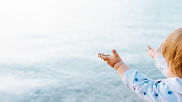 Vista laterale del bambino che gode della vista dell'acqua con la sabbia sulle mani