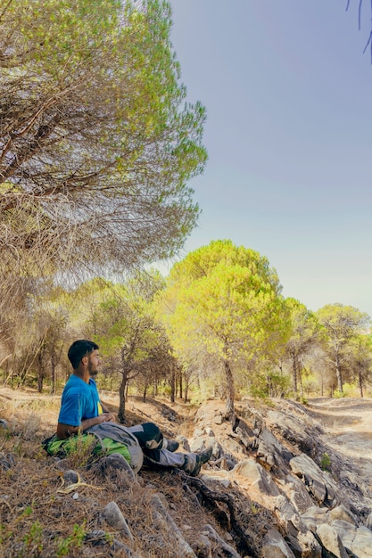 Side view of backpacker sitting under trees