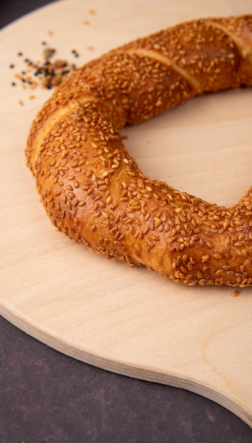 Free photo side view of bagel on wooden surface and maroon background