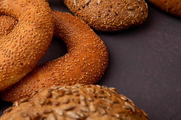 Side view of bagels with sandwich bread on maroon background with copy space