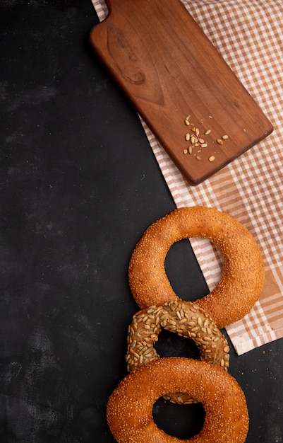 Side view of bagels with sunflower seeds on cutting board on wooden background with copy space