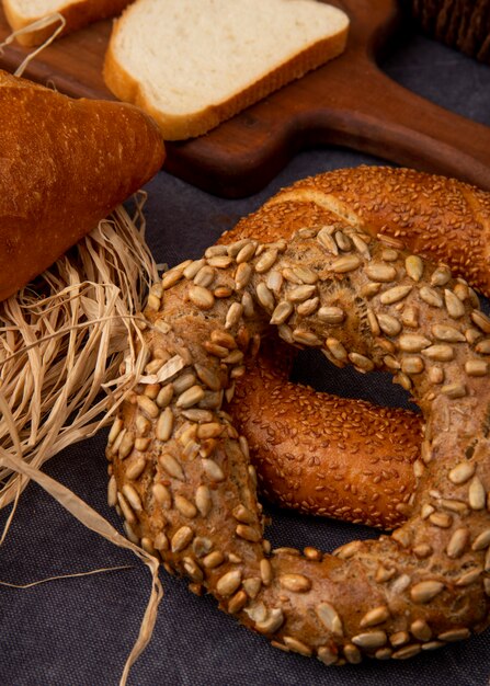 Side view of bagels with white bread slice and straw on maroon background