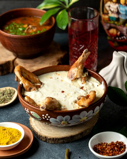 Side view of baked chicken with cheese in a clay bowl