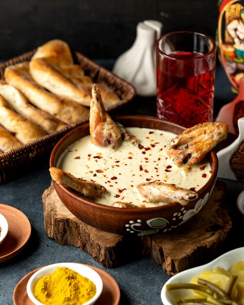 Side view of baked chicken with cheese in a clay bowl