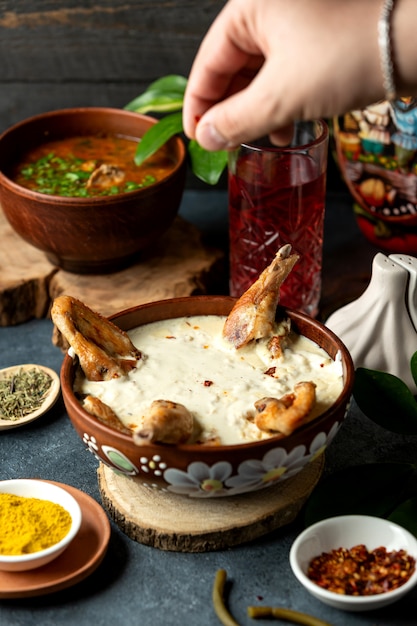 Side view of baked chicken with cheese in a clay bowl