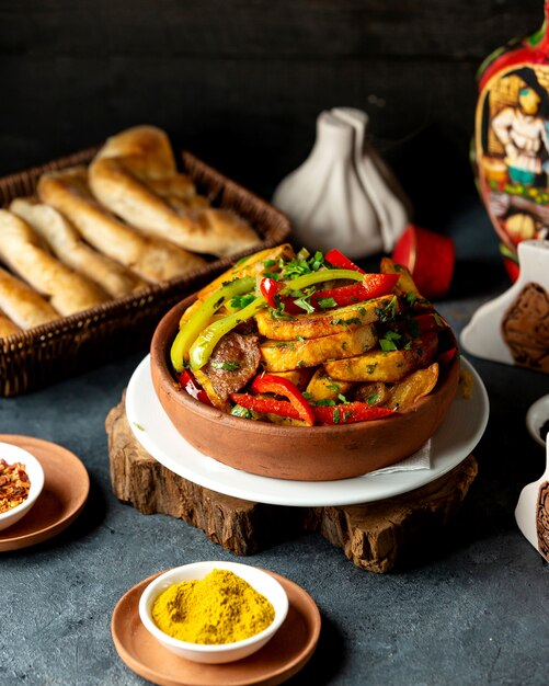 Side view of baked potatoes with lamb meat and vegetables in a clay bowl on the black table