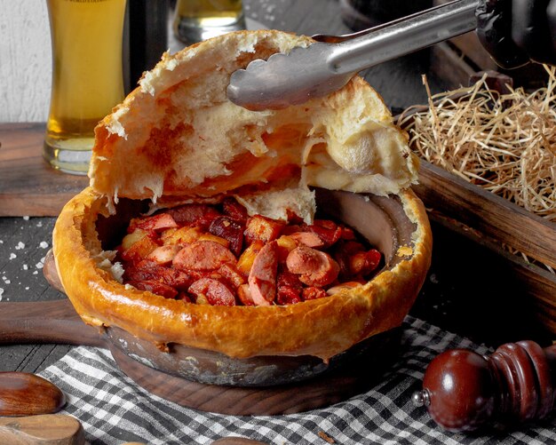 Side view of baked sausage in a clay bowl on rustic surface