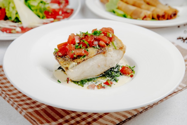 Side view of baked seabass with tomatoes