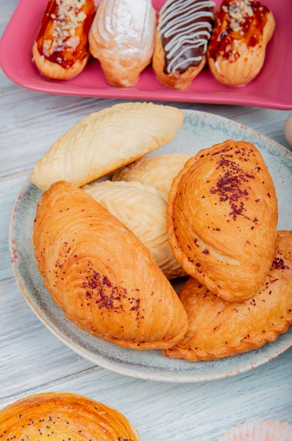 Side view of bakery products as badambura shakarbura goghal in plate with cakes on wooden surface