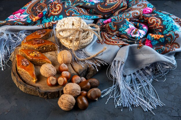 Вид сбоку на пахлаву с цельными орехами и рисовым хлебом на платке с кисточкой
