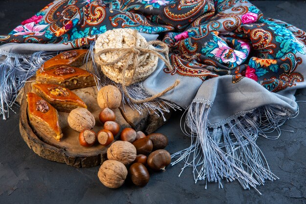 Side view of baklava with whole nuts and rice breads on shawl with tassel