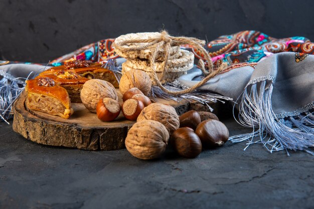 Side view of baklava with whole nuts and rice breads on shawl with tassel