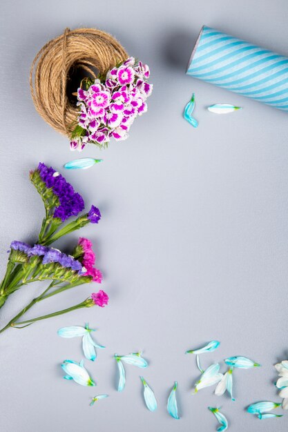 Side view of a ball of rope with purple color turkish carnation and statice flowers on white table with copy space