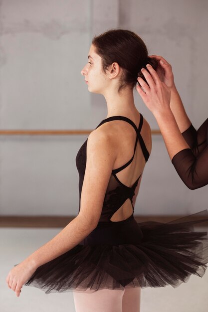 Side view of ballerina getting her hair bun fixed