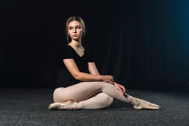 Side view of ballerina posing in tights and pointe shoes